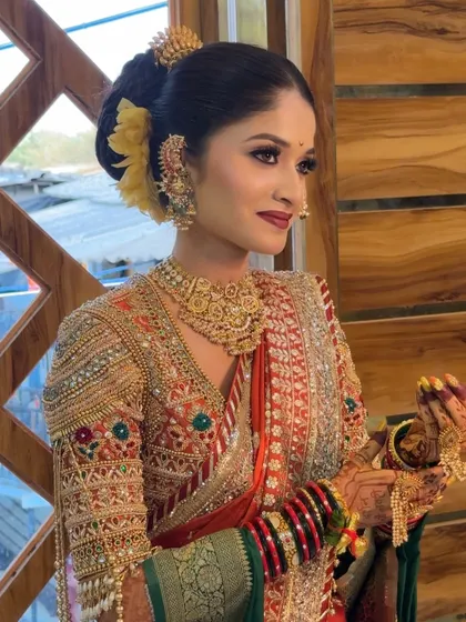 A candid shot of the bride in her orange and green Paithani, holding a 'khalbatta'.