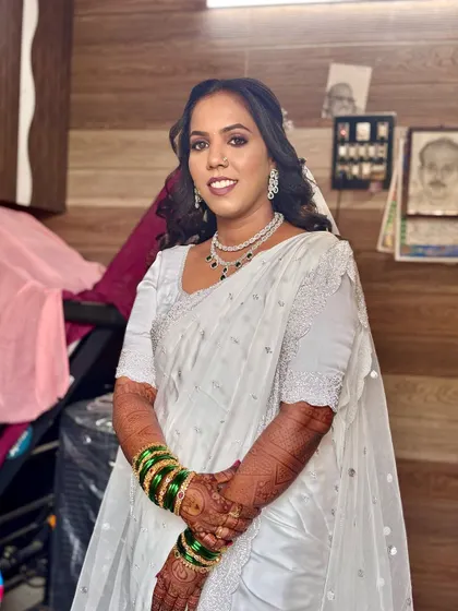 This Buddhist bride is wearing a beautiful white saree with green bangles. Her hair is styled in soft waves, creating a look of simple elegance.
