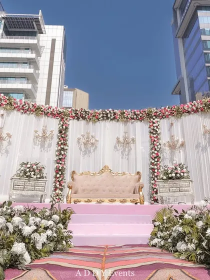 A wider angle of the outdoor floral stage, showing its impressive scale against the modern cityscape. This setup is perfect for daytime engagements or receptions, combining classic elegance with a contemporary urban setting.