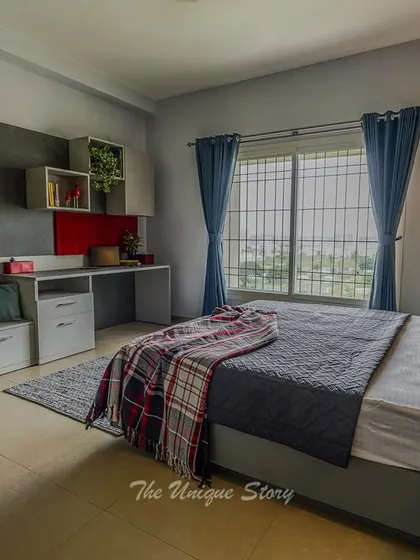 We designed this son's bedroom to be a functional and stylish space. It includes a built-in study desk with overhead storage cubes and a comfortable seating bench with drawers, all in a cool grey and red color palette.