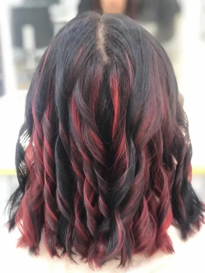 Adding highlights is a great way to create dimension. Here, I've woven striking red streaks through dark hair and finished with soft curls to really show off the contrast and movement in the style. This is a great option for a bold yet elegant change.