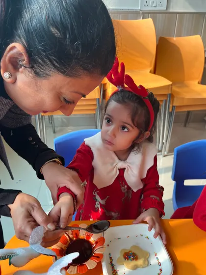 An instructor helps a young participant with her cookie, ensuring everyone can join in the fun.