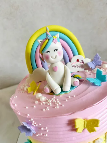 A close-up of a happy little unicorn sitting on a rainbow. The perfect topper for a magical cake.