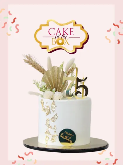 A chic and elegant cake for a 75th birthday milestone. The clean white design is beautifully accented with gold leaf, dried botanicals, and a stylish number topper.