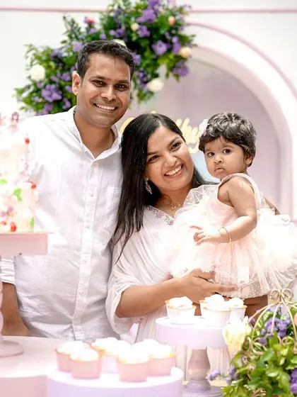A happy family photo at the custom-designed cake table. My goal is to create a beautiful backdrop where you can celebrate and capture these precious moments, like Aadhya's first birthday cake cutting.