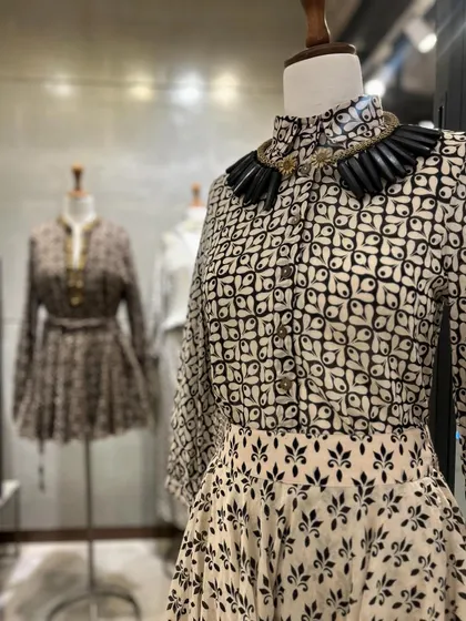 A detailed shot of the printed peplum top and skirt, paired with a bold, black collar necklace for a dramatic and stylish effect.