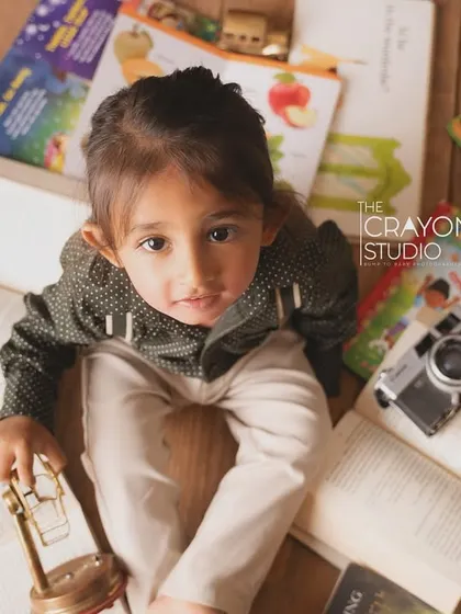 An overhead shot of the little explorer surrounded by books, a toy plane, and a vintage camera.
