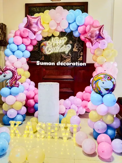 A pastel rainbow unicorn theme with a full balloon ring. This setup includes unicorn and star foil balloons and the name 'Kashvi' in lights.
