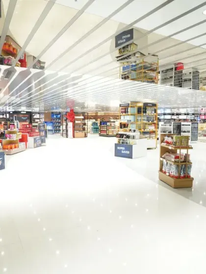 A very wide shot of the duty-free floor, showing the spacious aisles and ceiling architecture. This minimalist composition emphasizes the clean, modern environment of the airport shopping experience.