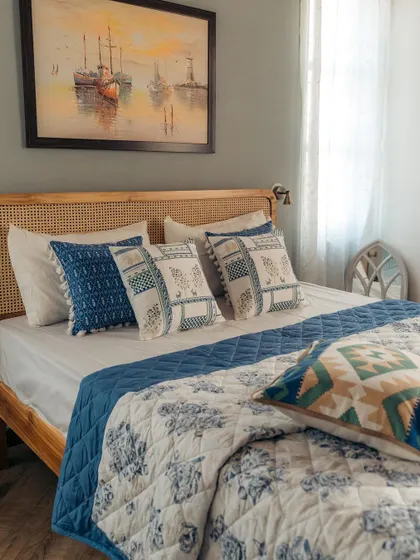 This wider shot shows the complete bedding set, including the blue floral quilt and matching bed runner. The layers of different blue tones and patterns create a rich and cohesive look.