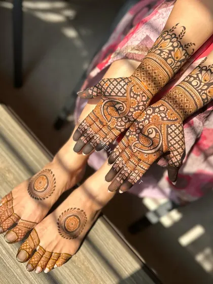 A complete bridal look with matching henna for hands and feet. The hands feature intricate peacock designs, while the feet have simple, elegant mandalas, creating a cohesive and beautiful set.