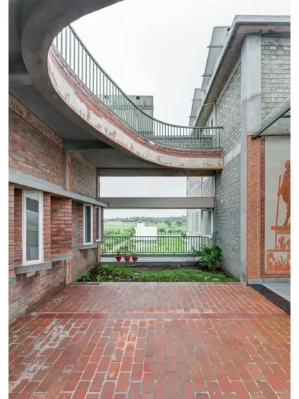 An open-air corridor at the ASA Office, with a curved bridge connecting two parts of the building. This space features a large mural of Mahatma Gandhi and overlooks the surrounding landscape.