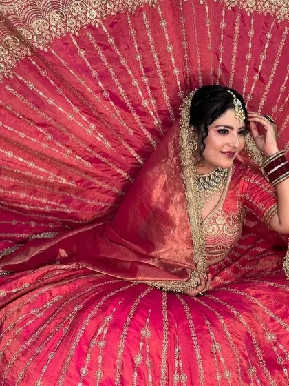 A dramatic shot showcasing the full expanse of a traditional red and gold lehenga, emphasizing its volume and intricate design.