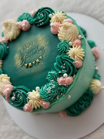 A side view of the emerald green ganache cake, showing the texture and detail of the piped buttercream flowers.