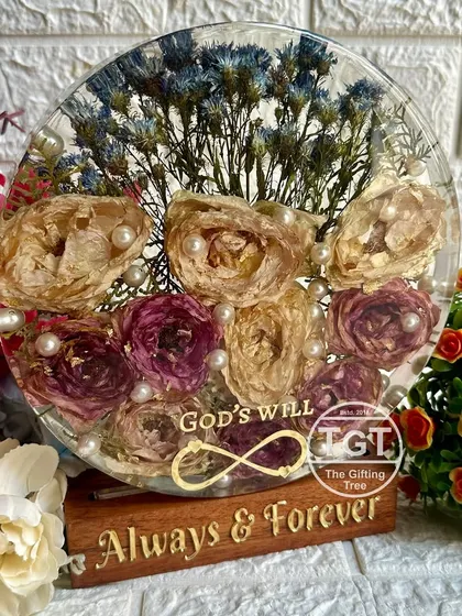 The combination of preserved flowers, pearls, and meaningful text makes this a truly special piece. The wooden stand adds a natural, warm touch.