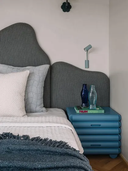 The master bedroom's custom bedside table and wavy headboard create a serene and stylish sleeping space.