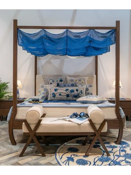 Our bespoke four-poster bed, designed for the Design Democracy event. The sleek wooden frame and curved legs mirror the fluid lines of the indigo canopy, creating a refined sanctuary.