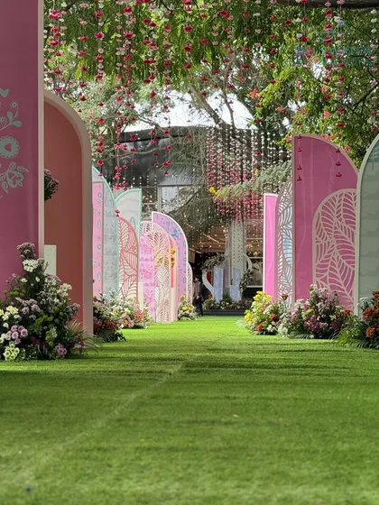 Looking down the long pathway of arches, with floral strings hanging from the trees above, creating a magical, multi-layered entrance.