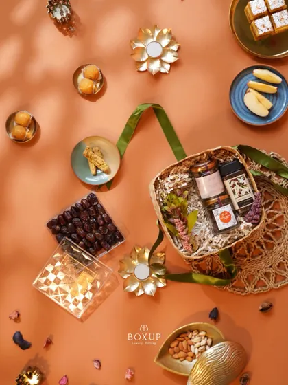 Everything you need for the season of Ramadan gifting in one basket. This top-down shot shows a palm leaf basket filled with dates, baklava, nuts, and decorative items.