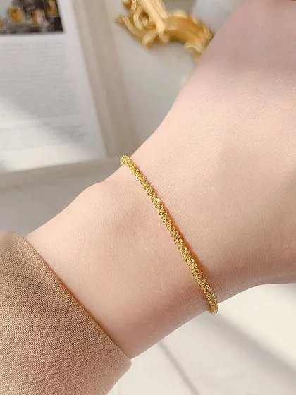 A model wearing the sparkling textured gold-toned bracelet, showing how it catches the light beautifully.