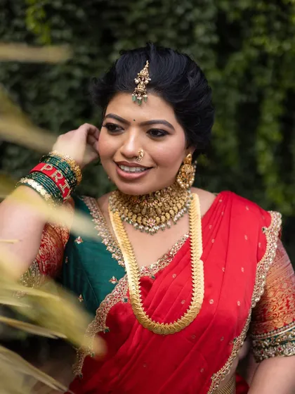 A touch of royalty for this pre-wedding look. The bride is wearing a beautiful red and gold half-saree, and her makeup is classic and elegant.