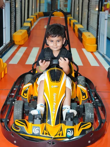 This little boy looks like a pro, confidently holding the steering wheel of his yellow go-kart.