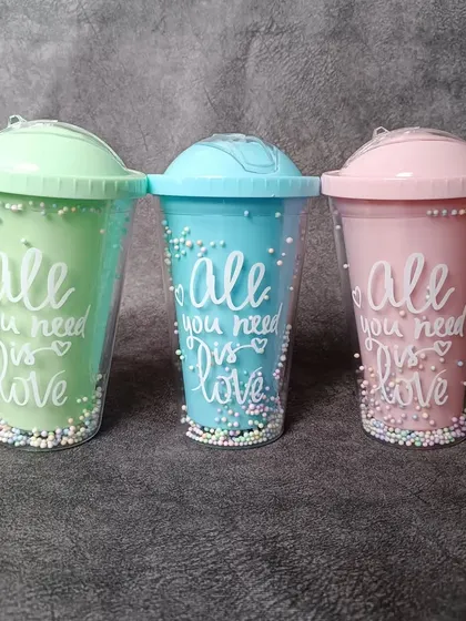 A lineup of the pastel 'All you need is love' sippers in mint green, sky blue, and soft pink. These make for a cheerful and practical gift.