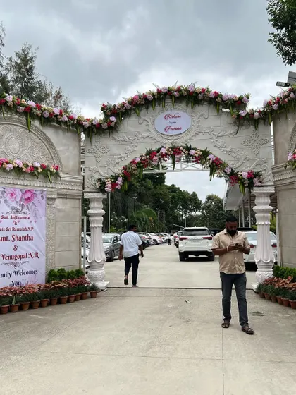 A grand, permanent-style entrance gate decorated with beautiful pink and white floral arrangements for a wedding. This shows how I can enhance the existing architecture of a venue.