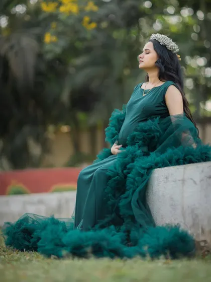 A peaceful, reflective moment captured as the mom-to-be sits serenely in her beautiful green gown.