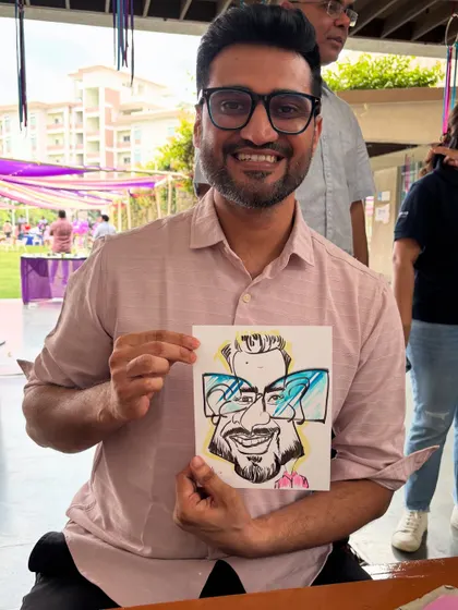 An alumnus from ISB posing with his cool caricature, a unique takeaway from the reunion.