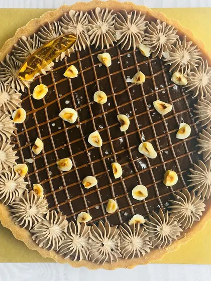 This Nutella Hazelnut tart is pure happiness. It features a creamy Nutella filling, a lattice of chocolate ganache, and is topped with toasted hazelnuts for a delightful crunch.