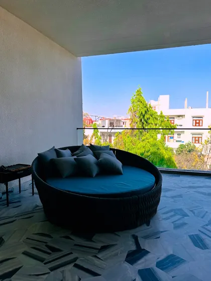 A comfortable daybed on a Jaipur balcony, offering a perfect spot for lounging and enjoying the view. The patterned marble floor adds a touch of luxury.