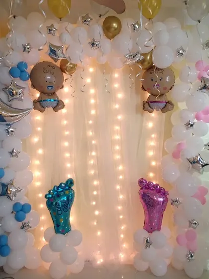 A dreamy, cloud-themed baby shower decoration. I used white balloon clusters to create a cloud effect, accented with a fairy light curtain and foil balloons of babies, a moon, and stars.