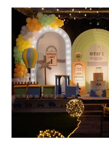 The vehicle-themed stage at night, with all the props and backdrops beautifully illuminated, creating a magical cityscape for the party.