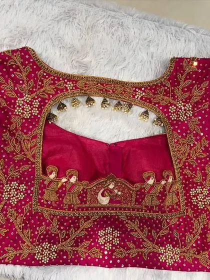 The back of the pink bridal blouse, featuring a stunningly detailed palanquin and peacock motif embroidered around the cutout.