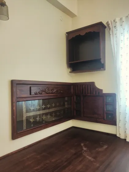 Another detail shot of the custom headboard, showing the beautiful woodwork and the embedded sari fabric. A wall-mounted pooja shelf adds a spiritual element to the room.