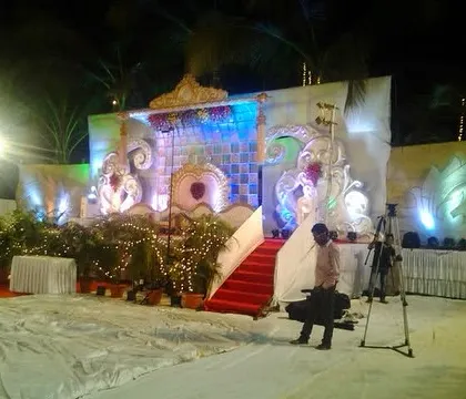 A wide shot of the outdoor reception setup, showing the stage, lighting rigs, and the videography team at work, highlighting the scale of the event.