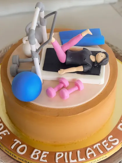 A close-up of the "Bride to be Pilates Pilla" cake, showing the detailed fondant work on the figure and equipment.