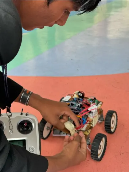 A student making last minute adjustments to their remote controlled competition robot. These moments of intense focus and problem solving under pressure are where the real learning happens.