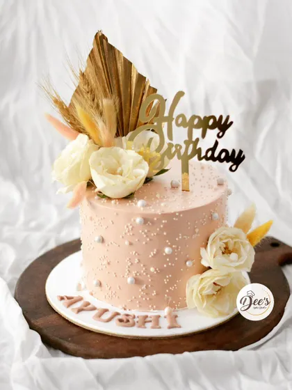 This boho-chic cake is perfect for a stylish birthday. It features a soft peach buttercream, pearl sprinkles, and is elegantly decorated with dried flowers and palms.