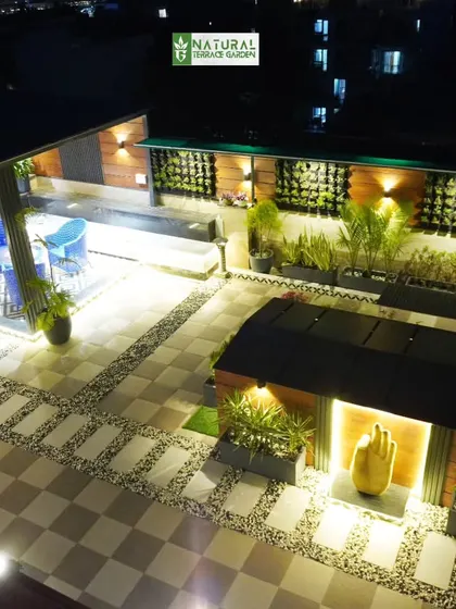 An aerial night view of a completed terrace in Palam Vihar, Gurgaon. The layout includes multiple seating areas, a swing, and extensive pathway lighting.