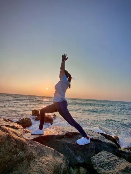 A silhouette of Virabhadrasana II (Warrior II) against a sunrise over the ocean. Yoga is an addition of energy, strength, and beauty to the body, mind, and soul.
