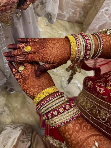 A close-up of the beautiful henna stain, complemented by the bride's colorful bangles.