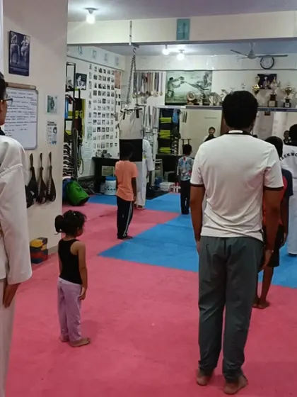A class of beginners, some in uniform and some not, learning the basic ready stance.