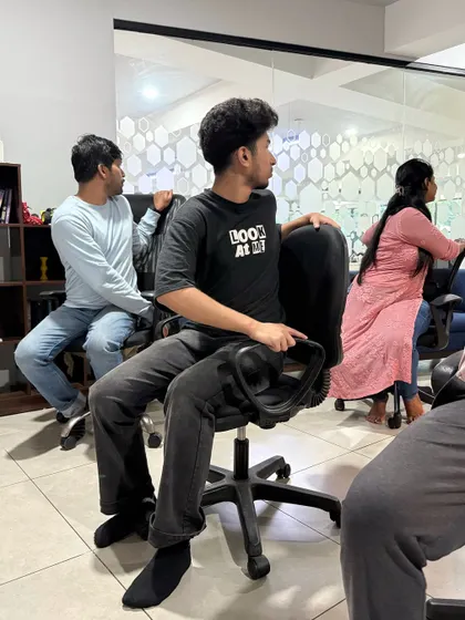 Employees at Skills Outsource practicing a gentle spinal twist in their chairs. This movement helps to improve digestion and increase mobility in the spine.