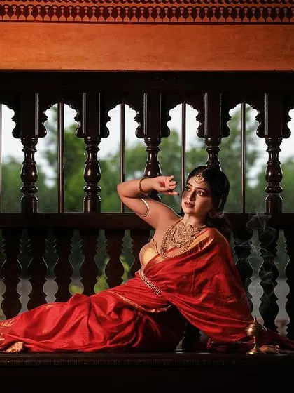 A regal portrait series inspired by the queens of Tulunadu. The model is adorned in a stunning red saree and antique-style jewelry, captured in a heritage location to enhance the royal theme.