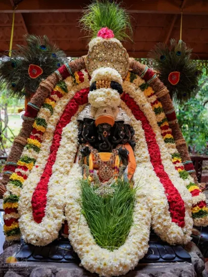The Pratapa Ganapati idol adorned with an elaborate garland of white flowers and sacred durva grass. This form of Ganesha is worshipped for courage and victory.