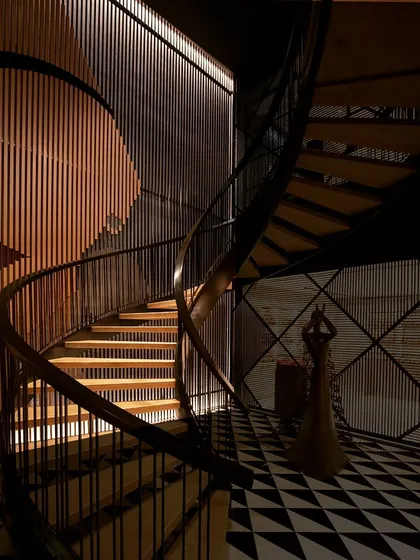 This spiral staircase is a centerpiece, where light is the primary architectural material. I used a technique called wall grazing, with linear fixtures at both the ceiling and floor, to cast dramatic shadows and highlight the texture of the vertical slats, transforming a simple passage into a powerful visual journey.