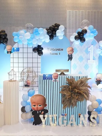 This Boss Baby theme uses a cool palette of black and blue. The backdrop features a modern grid pattern, character cutouts, and themed props like a miniature bicycle and birdcage for a stylish look.