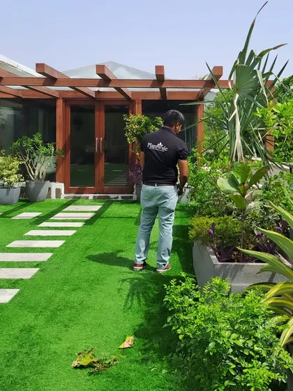 Here, a member of my team is inspecting a newly installed artificial lawn in a residential garden. I offer maintenance and inspection services to ensure your green space always looks its best.